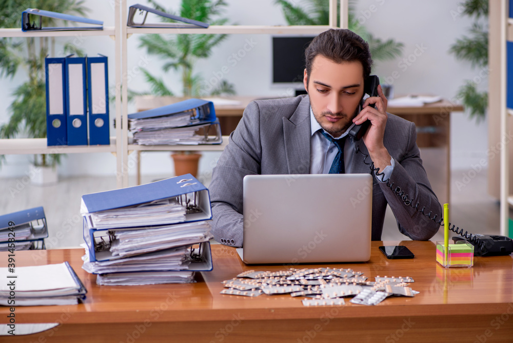 Young male sick employee suffering at workplace Young male sick employee suffering at workplace