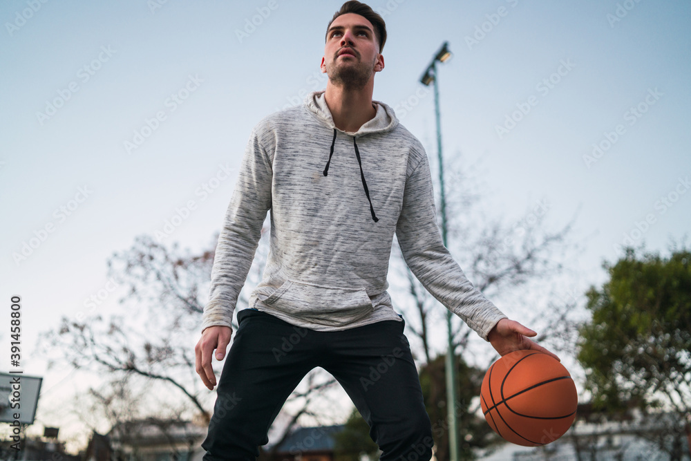 Naklejka premium Young man playing basketball on street