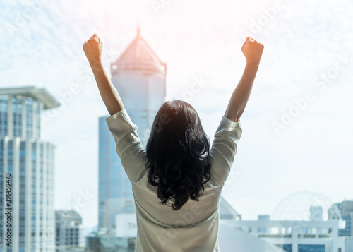 Woman power and girl strength in business achievement, winning and success with strong businesswoman leader in office raising fists with ambition looking forward to city building urban background