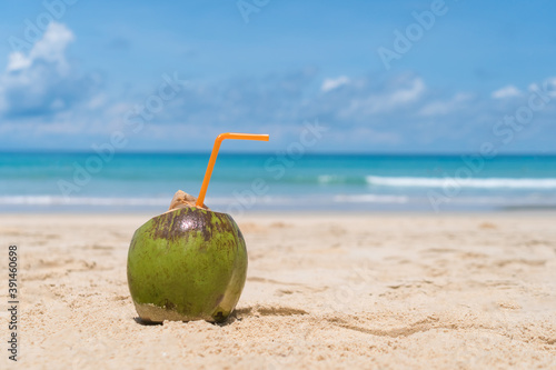 Fresh coconut on sand at summer beach blue sky.