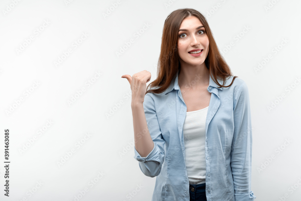 Beautiful girl pointing and showing with thumb to the side with happy face, smiling. Presenting your product Beautiful girl pointing and showing with thumb to the side with happy face, smiling. Presenting your product