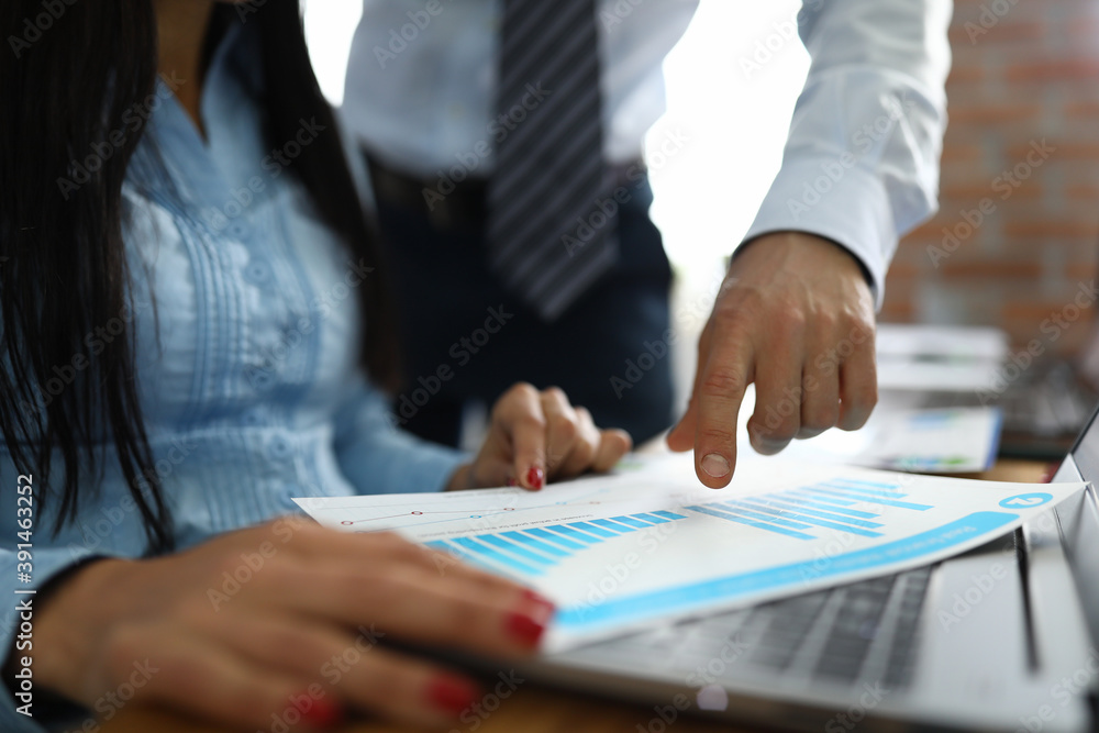 Man points to woman on commercial business charts. Graph analysis methods for companies concept Man points to woman on commercial business charts. Graph analysis methods for companies concept