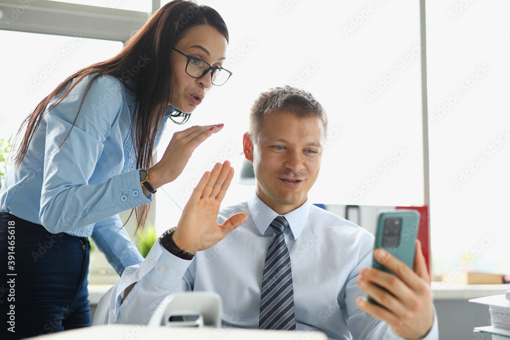 Fototapeta premium Businesswoman and businessman at the work desk hold smartphone in their hands Business online communication in business sphere concept