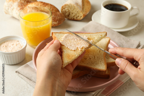 Female hands spread butter on toast bread, close up