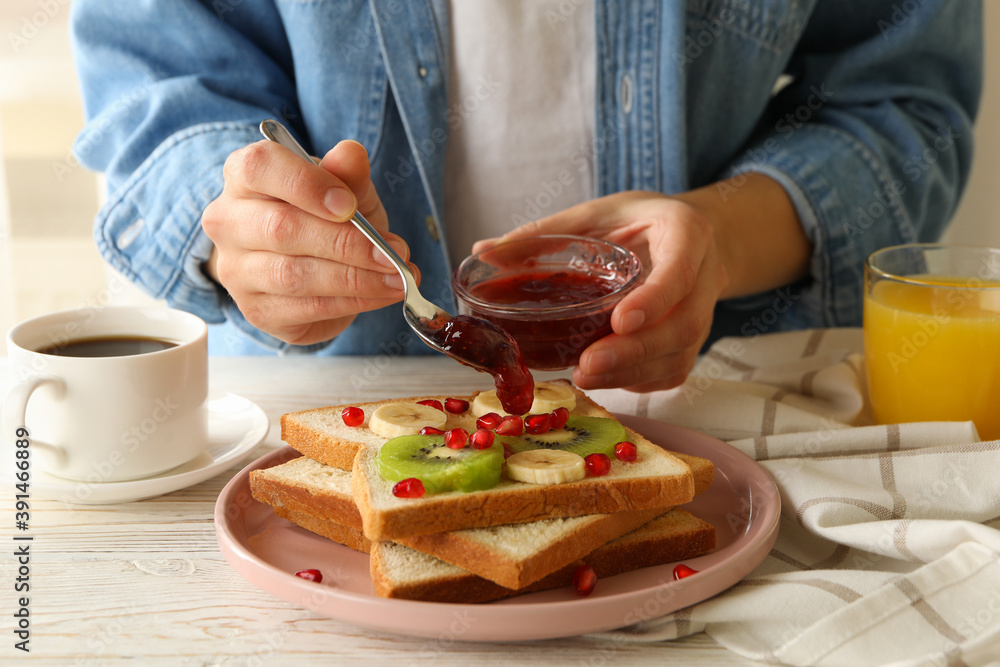 Woman pour jam on tasty toast with fruits