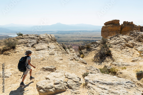 Boy with a backpack striding on a trail through an open landscape, protected canyon lands.  photo