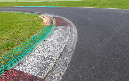 Close up of rough dirty curb at left turn on motor sport track with green field and black asphalt © fabioderby