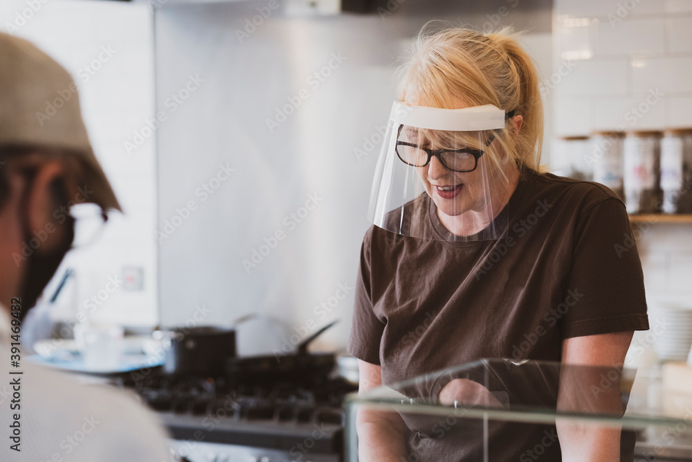 Blond waitress wearing face mask working in a cafe. Blond waitress wearing face mask working in a cafe.