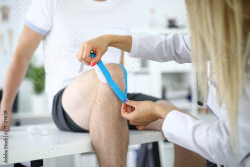 Nurse glues kinesio tape to patient s knee. What kinesio tapes are and how to choose them concept