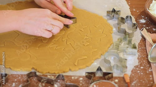 women's hands cut homemade Christmas gingerbread from the dough, preparing for baking.