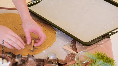 women's hands cut homemade Christmas gingerbread from the dough, preparing for baking.