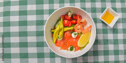 Fresh salad with seafoods, tomato and herbs. Red salmon, small shrimps, avocado, cherry tomatoes.