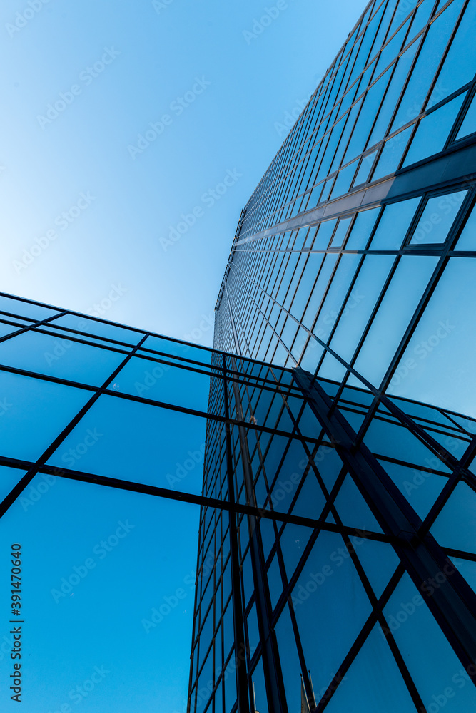 Looking up a tall glass and steel high-rise building..