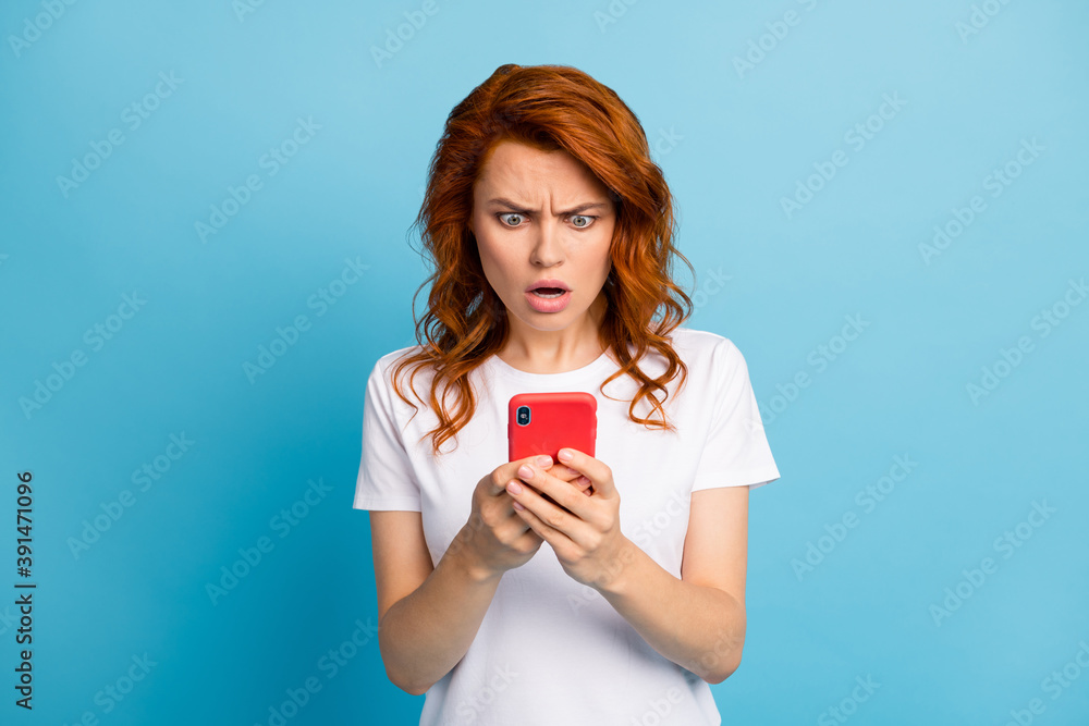 Photo portrait of offended girl holding phone in two hands isolated on pastel blue colored background Photo portrait of offended girl holding phone in two hands isolated on pastel blue colored background