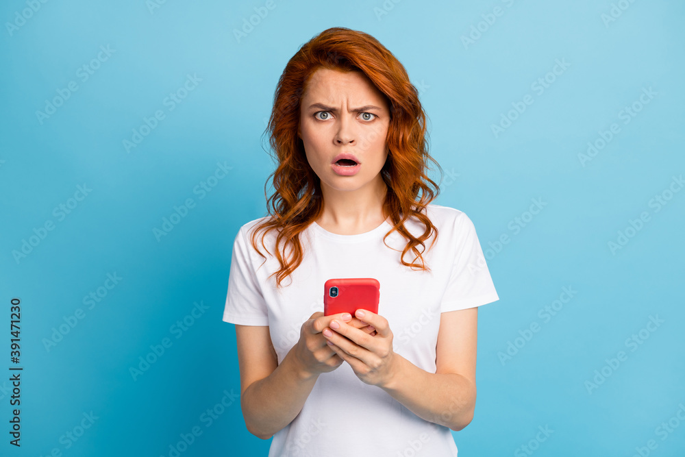 Photo portrait of unhappy girl holding phone in two hands isolated on pastel blue colored background Photo portrait of unhappy girl holding phone in two hands isolated on pastel blue colored background
