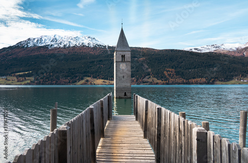 Tablou pe pânză Famous submerged church steeple arising from the alpine Resia Lake, in the town of Curon Venosta, in the italian Dolomite region of Trentino Alto Adige