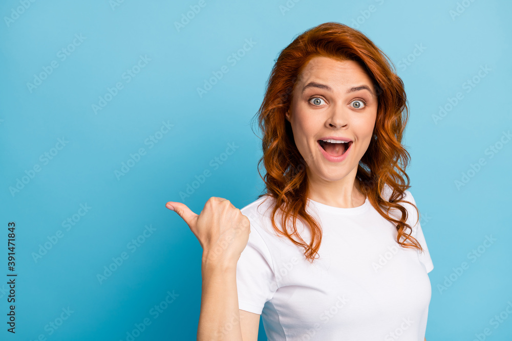 Photo portrait of shocked girl pointing finger behind back at blank space isolated on pastel blue colored background Photo portrait of shocked girl pointing finger behind back at blank space isolated on pastel blue colored background
