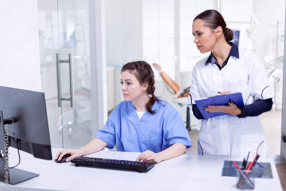 Dentist and nurse in in stomatolog office reception looking at s Stomatology assistant and teeth doctor discussing in lobby of dental office Dentist and nurse in in stomatolog office reception looking at s Stomatology assistant and teeth doctor discussing in lobby of dental office