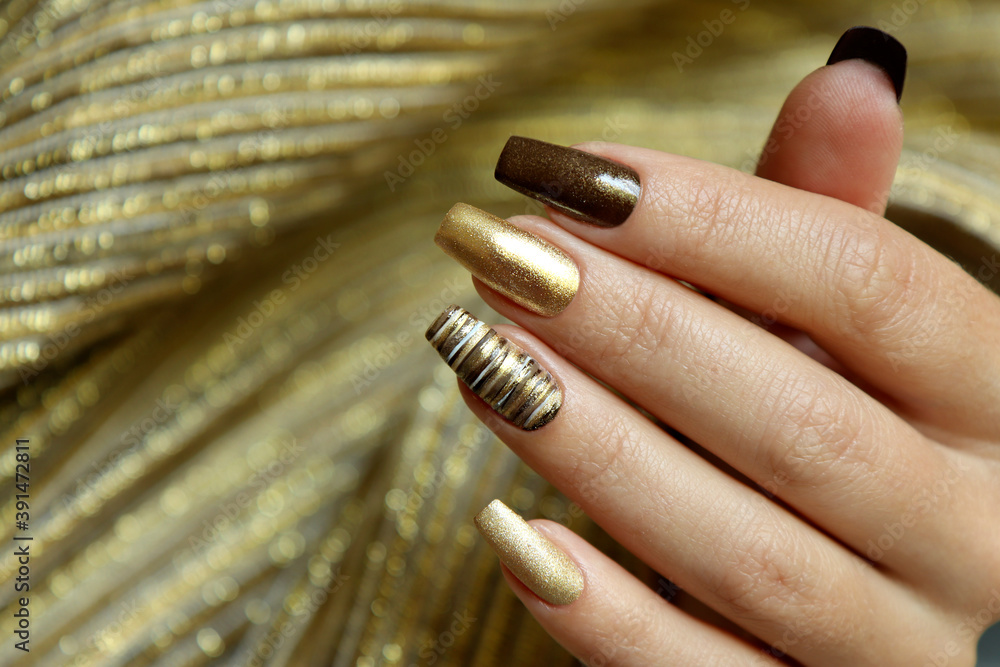 Fashionable manicure with a matte Golden color of nail Polish and brown on  a long nail shape. Stock Photo | Adobe Stock