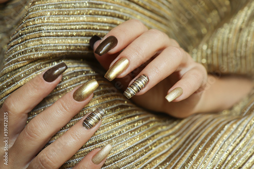 Fashionable manicure with a matte Golden color of nail Polish and brown on a long nail shape.