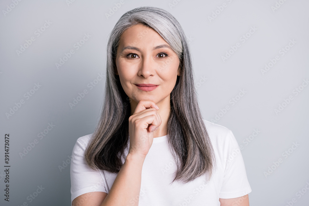 Photo of pensive retired grandmother finger chin look camera wear white t-shirt isolated grey color background Photo of pensive retired grandmother finger chin look camera wear white t-shirt isolated grey color background