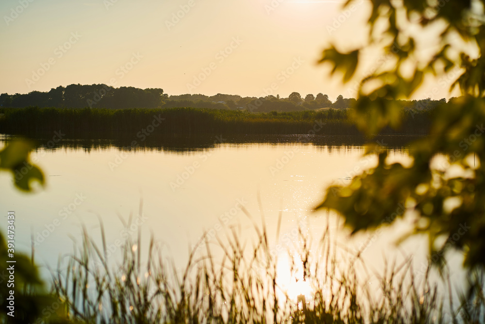 Sunset landscape over beautiful river and leaves in the foreground Sunset landscape over beautiful river and leaves in the foreground