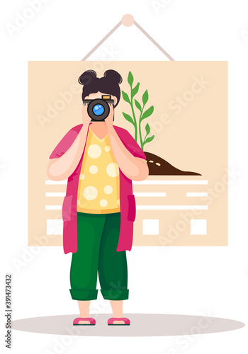 Girl standing and adjusting the lens. Photographer with poster with a planted tree on background. Greening the planet. Woman takes pictures. A female character prepares camera for a photo shoot