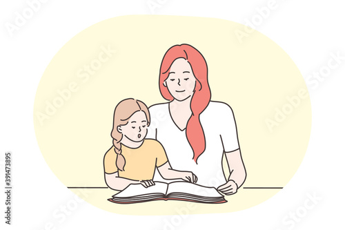 Happy leisure and activities at home with children concept. Young woman mother cartoon character reading, learning letters or words together with her small daughter at home. Relax, rest, family