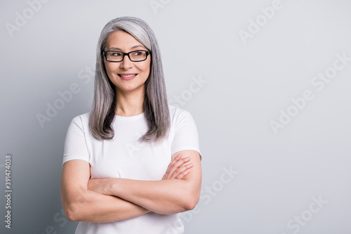 Photo of mature old lady toothy smile folded arms look empty space wear specs white t-shirt isolated grey color background