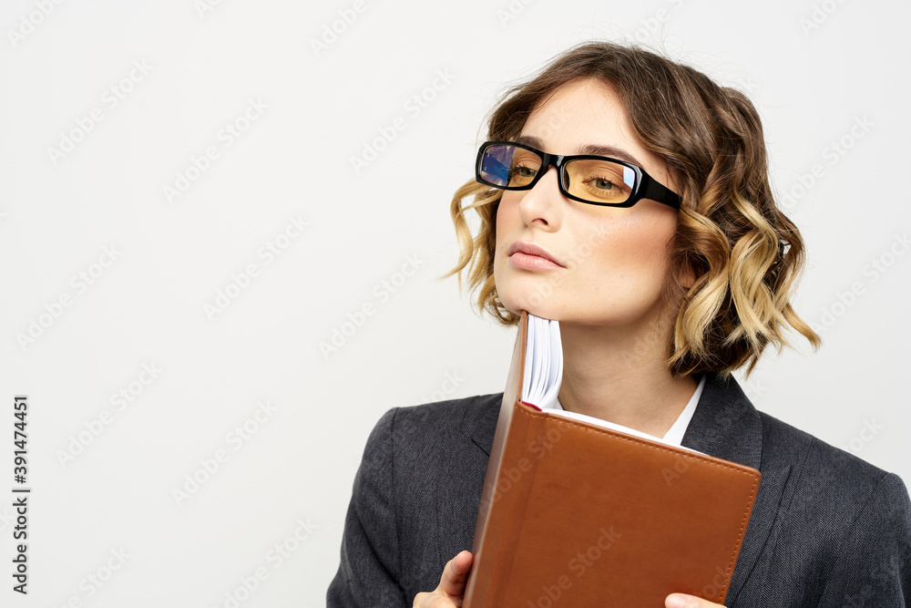 Business woman with notepad and glasses work light background cropped view of suit model. Business woman with notepad and glasses work light background cropped view of suit model.
