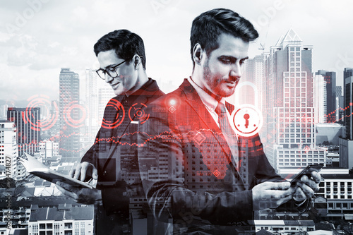 Two handsome businessman in suits working on project to protect clients confidential information at cybersecurity compliance division. IT lock icons over Kuala Lumpur background.