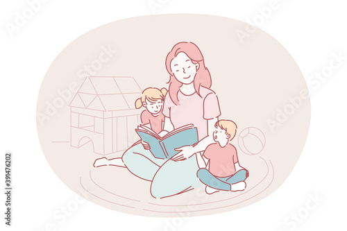 Happy leisure and activities at home with children concept. Young woman mother cartoon character sitting on carpet together with son and daughter and reading book for them at home. Relax, rest, family
