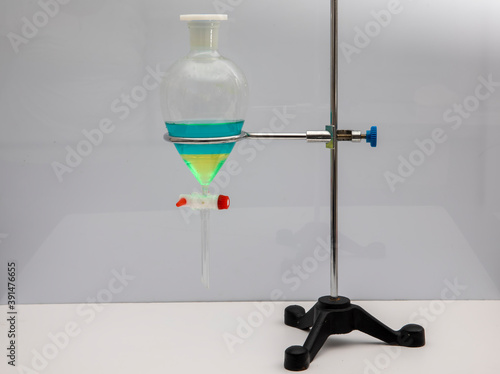 The study Separating by filtration the component substances from liquid mixture in Lab. Separating natural product use dichloromethane with water have two layer blue and yellow in separating funnel photo