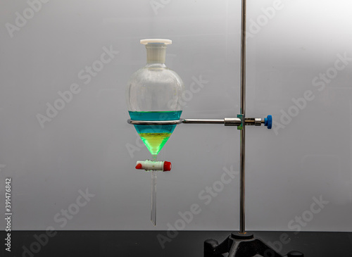 The study Separating by filtration the component substances from liquid mixture in Lab. Separating natural product use dichloromethane with water have two layer blue and yellow in separating funnel photo