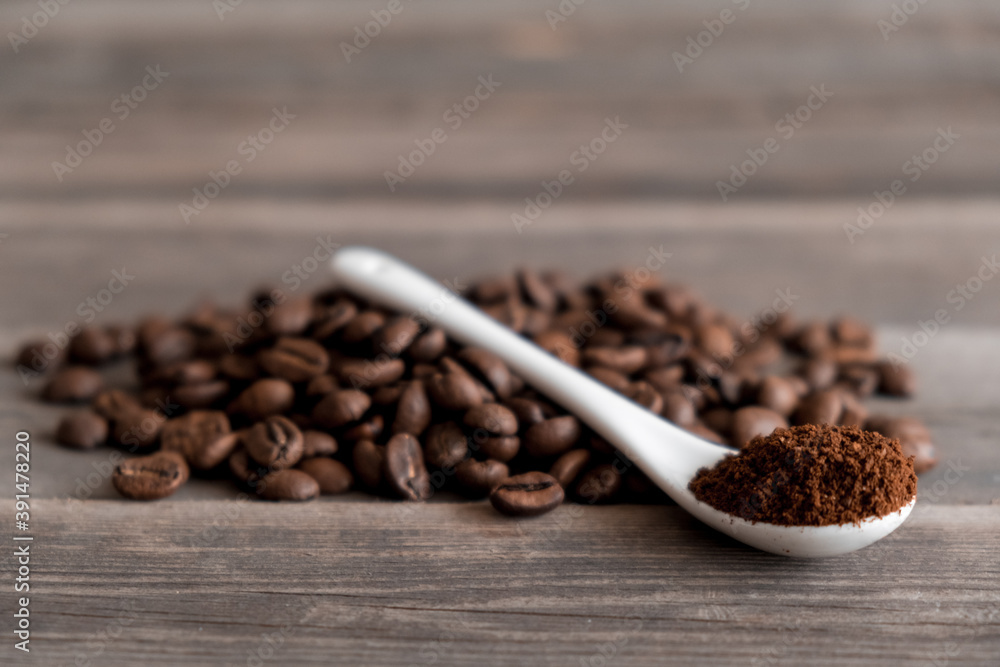 white ceramic spoon with ground coffee on a wooden background Fried Arabica grains. white ceramic spoon with ground coffee on a wooden background Fried Arabica grains.