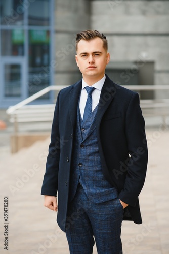 High fashion look.Young stylish confident handsome businessman model in suit clothes walking in the street.