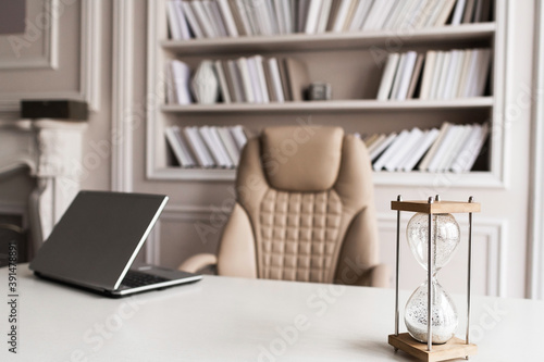 Business workplace with a sand wach and a laptop on the table. Timing and deadline concept. photo