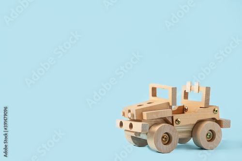 Wooden car toy on blue background with copy space for text.