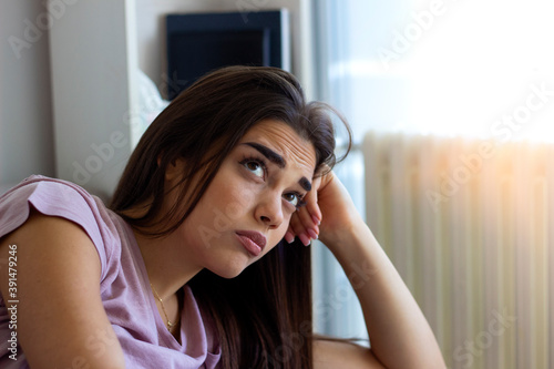 Young hopeless woman suffering from depression.Sad girl sitting alone.Cropped shot of anxious worried woman sitting on couch at home.Frustrated confused female feels unhappy, problems in personal life