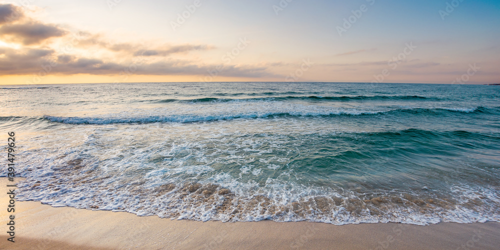 sunrise at the sea. beautiful summer landscape on the sandy beach. green waves rush on the shore in golden light