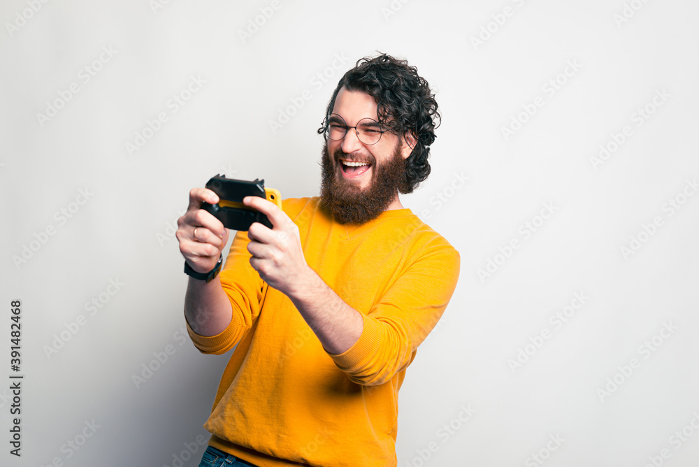 A happy young man is playing with a joystick in his phone . A happy young man is playing with a joystick in his phone .