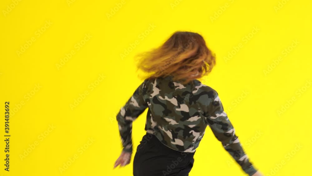 Woman dancing hip hop against the background of a yellow wall. Isolated. Medium long shot Woman dancing hip hop against the background of a yellow wall. Isolated. Medium long shot
