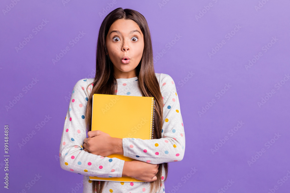 Photo portrait of amazed shocked girl hugging yellow book wearing sweater staring isolated on bright purple color background Photo portrait of amazed shocked girl hugging yellow book wearing sweater staring isolated on bright purple color background