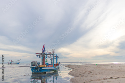 Wooden small fishing boat with Thai flag was moored and floated on water near the sandy beach © Hatori_Shisuka