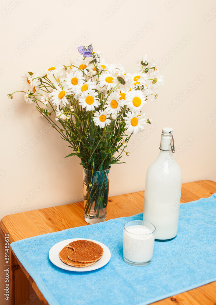 Simply stylish wooden kitchen with bottle of milk and glass on table, summer flowers camomile, healthy foog moring concept Simply stylish wooden kitchen with bottle of milk and glass on table, summer flowers camomile, healthy foog moring concept