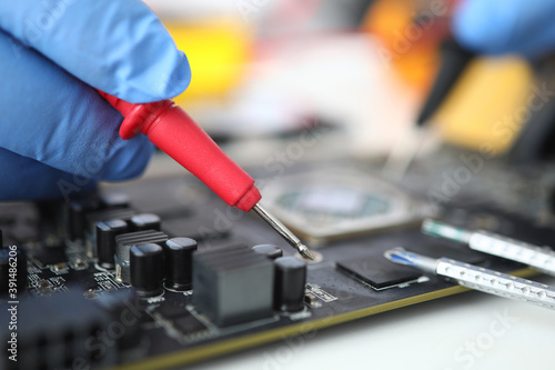 Gloved master holds probe over microcircuit. Repair and maintenance of e microcircuits concept