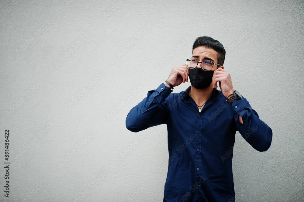 Middle eastern entrepreneur wear black face mask and eyeglasses against white wall. New normal life after coronavirus pandemia. Middle eastern entrepreneur wear black face mask and eyeglasses against white wall. New normal life after coronavirus pandemia.