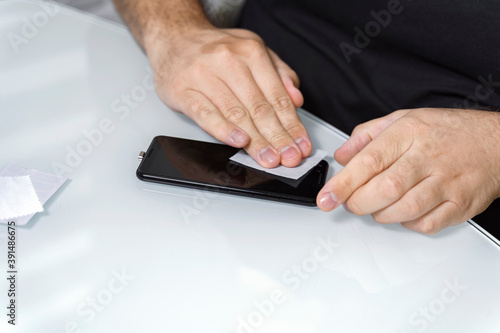 Cleaning smartphone screen with alcohol wipe to install protective glass. Close up.