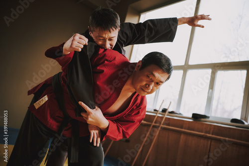 A master in a red kimono throws an opponent.