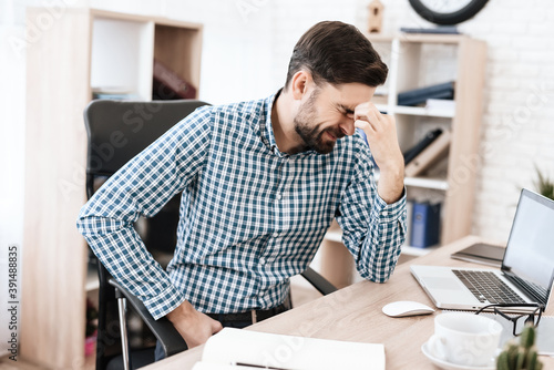 Man suffers severe pain while sitting at his desk.